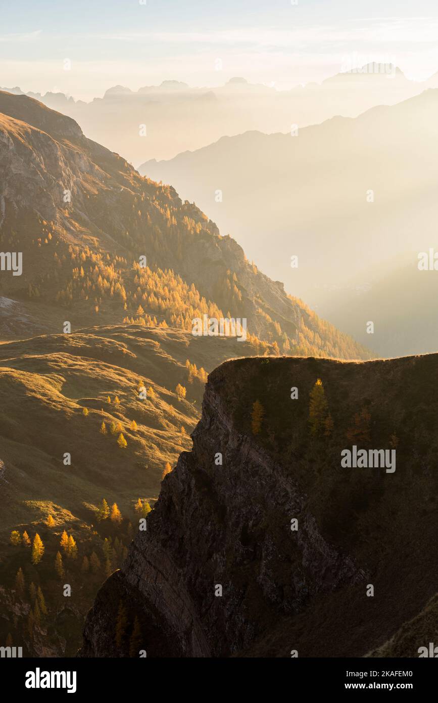 Oblique rays of sunlight illuminate the autumnal landscape with valleys and mountain ranges of the Civetta Group and Ampezzo Dolomites, Passo di Giau Stock Photo