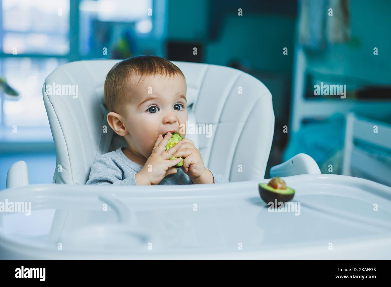 Little adorable baby eating avocado. Vitamin and healthy food for small