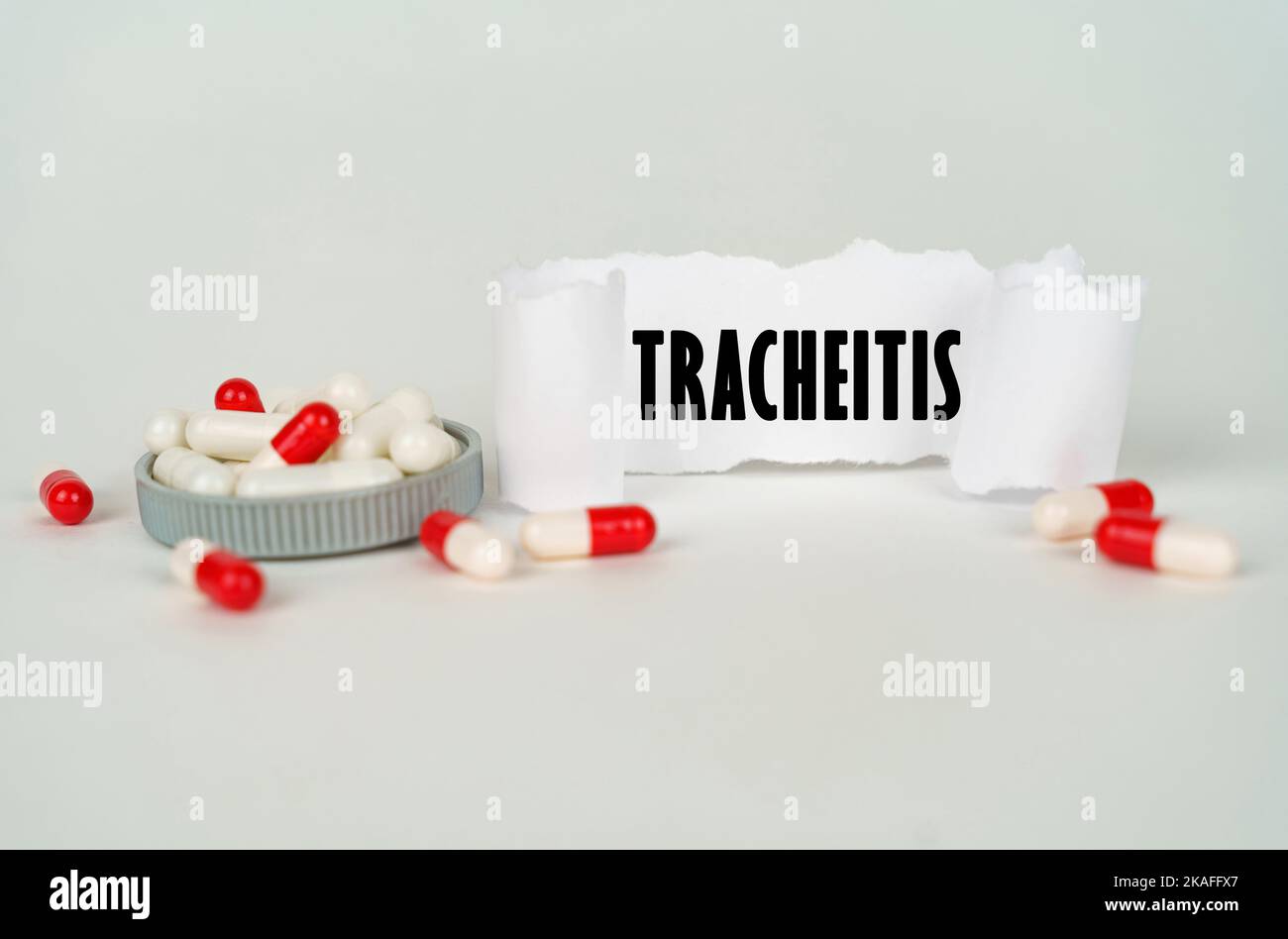 Medical concept. On a gray background, medical capsules and a paper plate with the inscription - Tracheitis Stock Photo