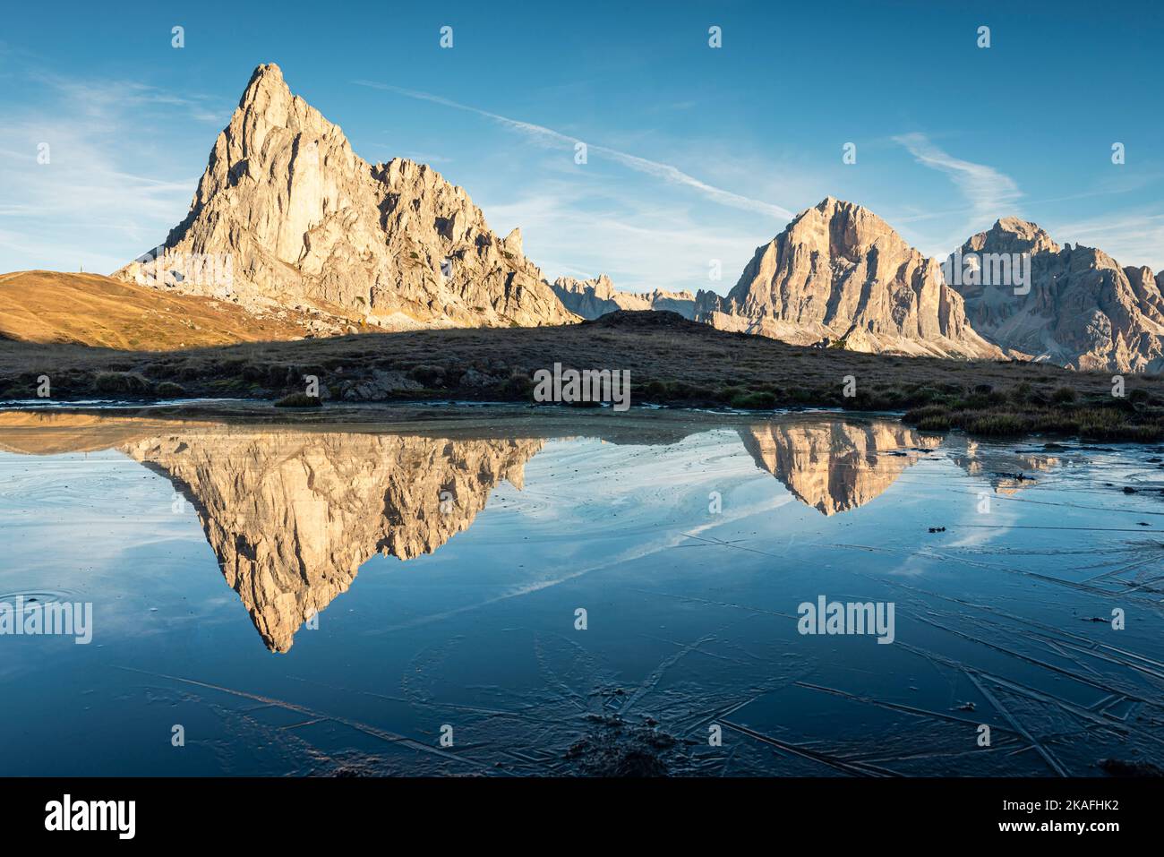 The Ra Gusela and Tofane di Rozes mountains reflected in the water and ice of a lake on a frosty autumn morning at Passo di Giau, Dolomites, Italy Stock Photo