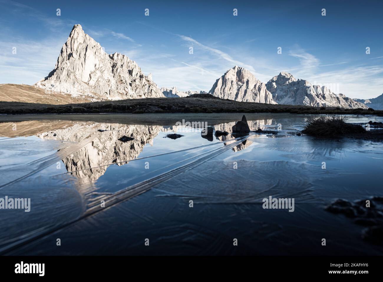The Ra Gusela and Tofane di Rozes mountains reflected in the water and ice of a lake on a frosty autumn morning at Passo di Giau, Dolomites, Italy Stock Photo