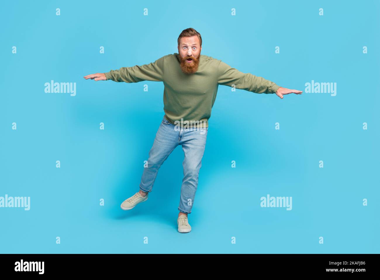 Full size photo of handsome young guy nervous try keep balance walk invisible tightrope wear khaki look isolated on cyan color background Stock Photo
