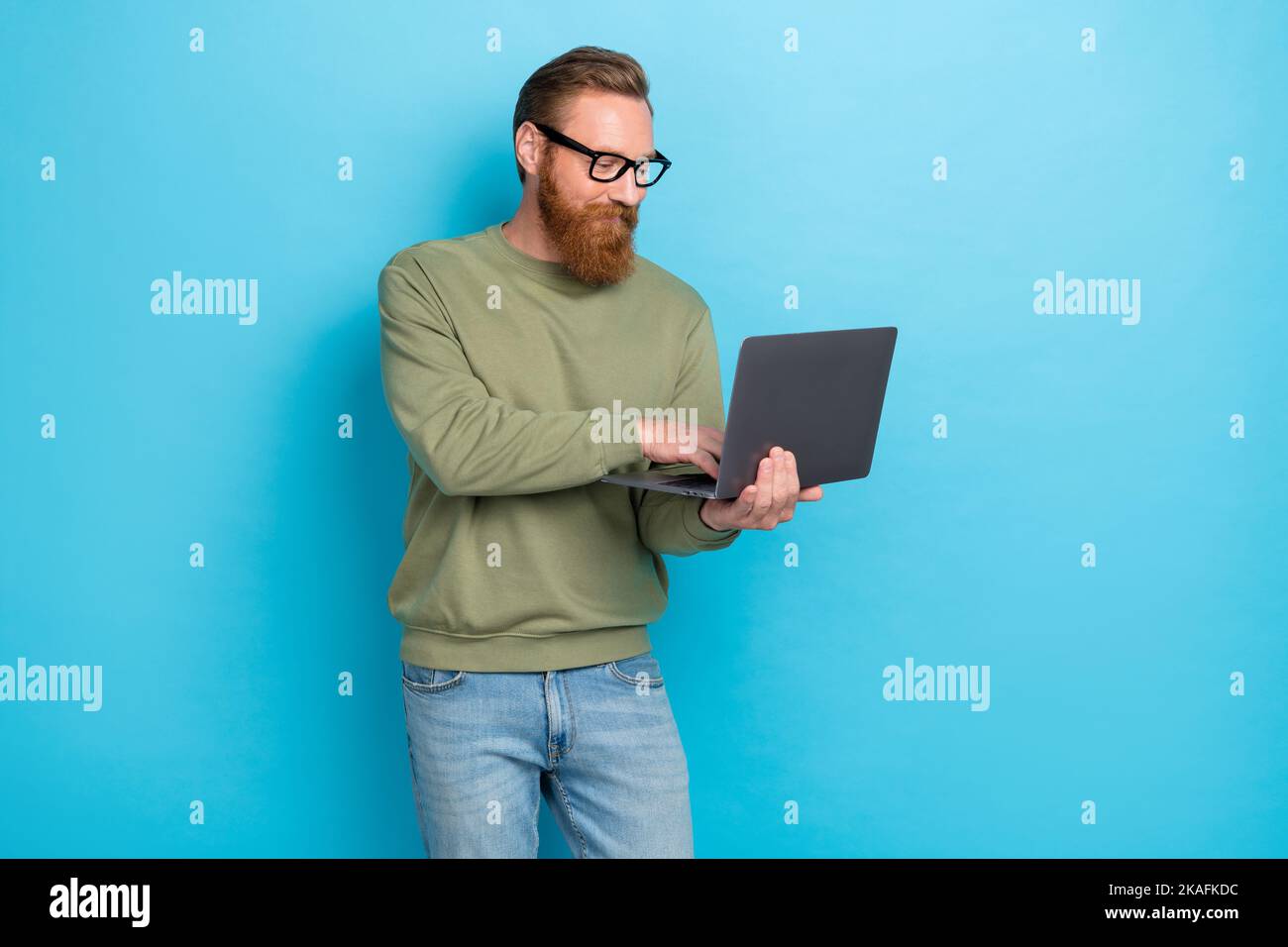 Photo portrait of nice young man working laptop apple macbook samsung dressed stylish khaki look isolated on aquamarine color background Stock Photo
