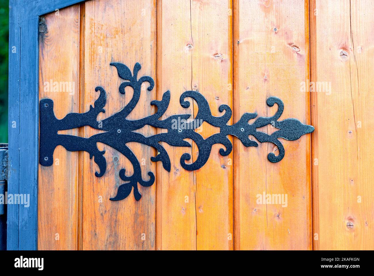 Black metal door hinge screwed to a wooden gate Stock Photo
