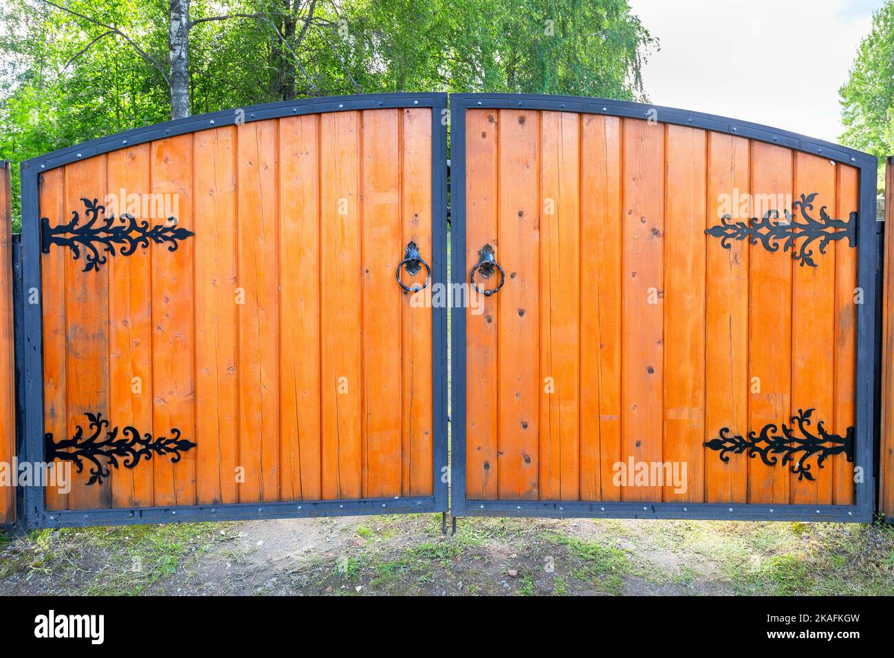 Big new wooden gate with metal knobs and door hinges Stock Photo