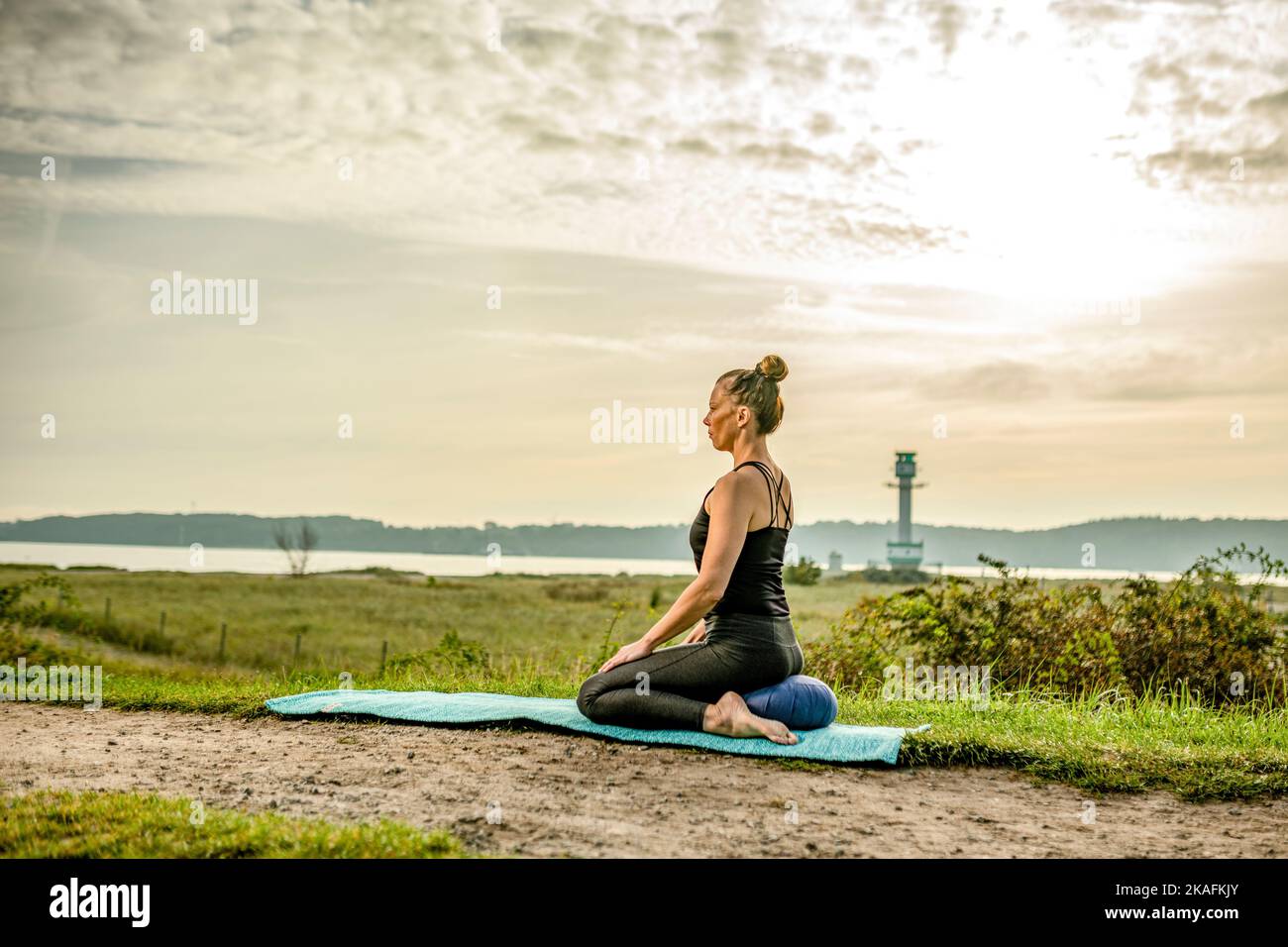 A woman in a sitting position on a yoga mat on the grass. Concept of ...