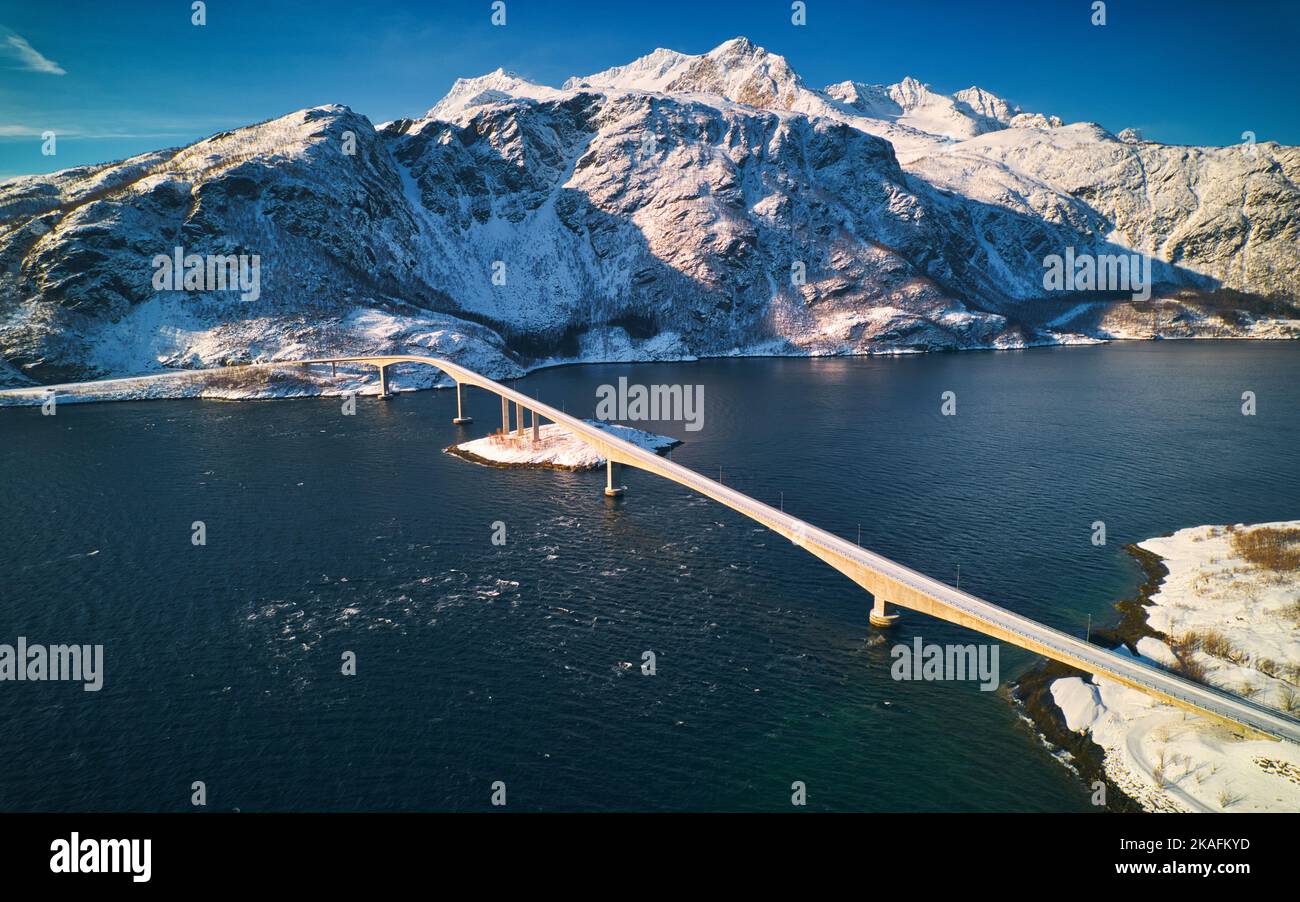 The aerial view of the Mjosund bridge against the background of snowy ...
