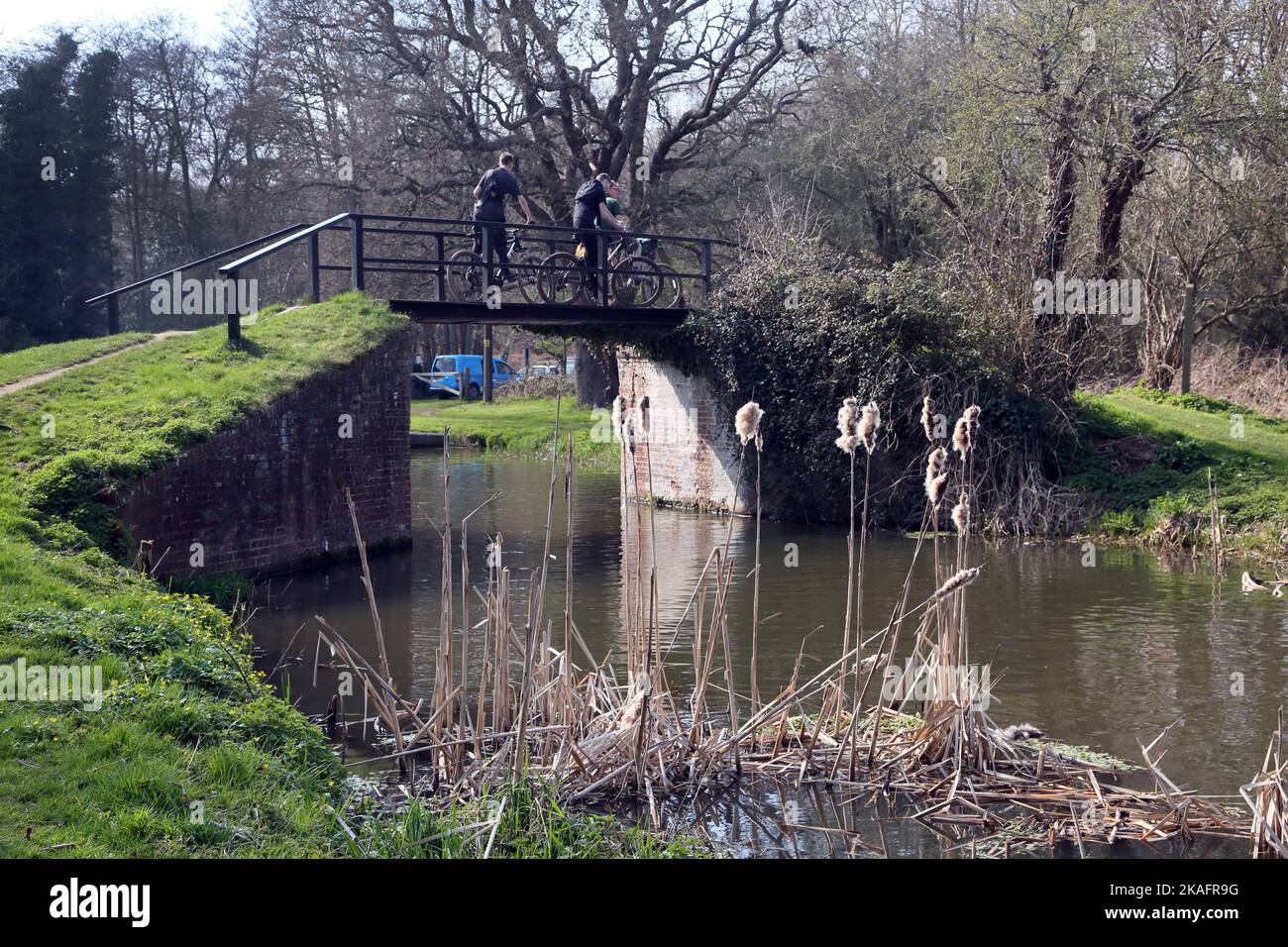 Cyclists going over footbridge at walsham lock river wey navigation surrey england Stock Photo