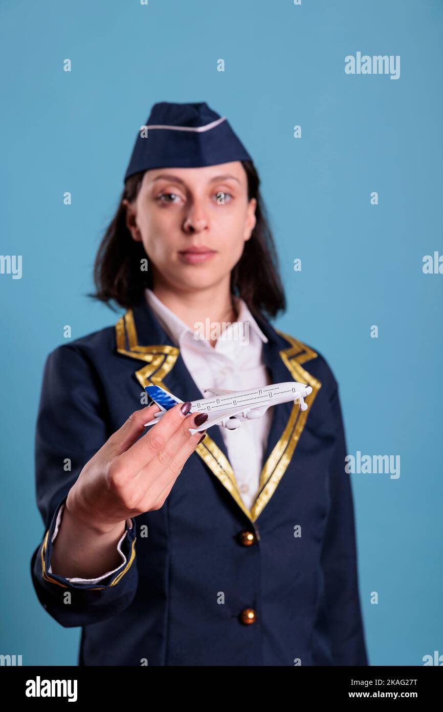 Portrait of stewardess holding airplane model, flight attendant wearing