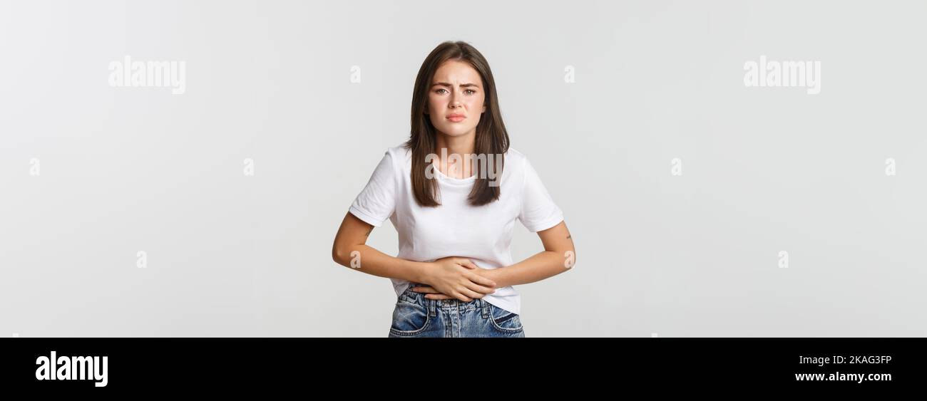 Woman having stomach ache, bending and holding hands on belly