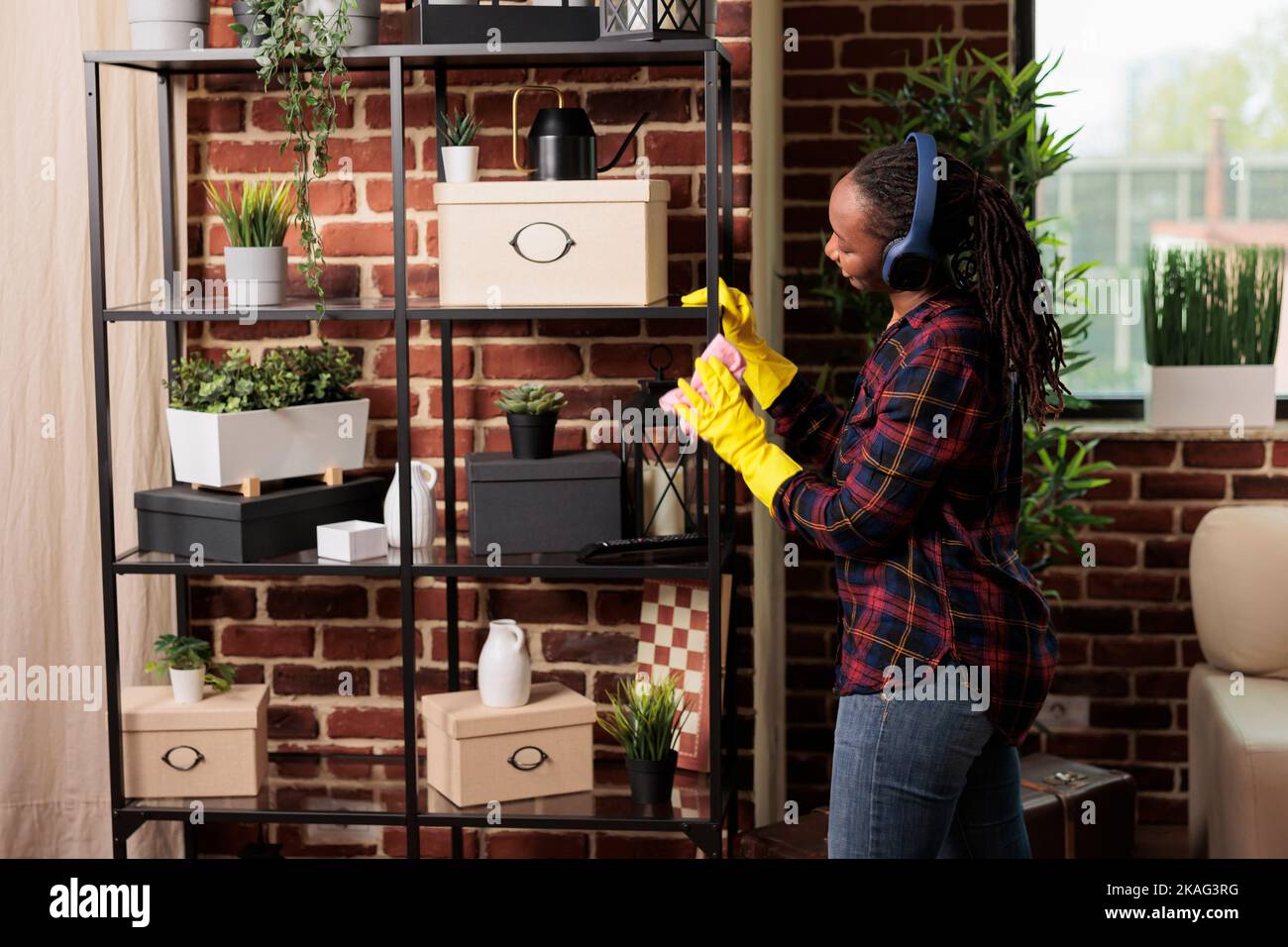 Housewife dusting furniture shelves in apartment, taking care of all