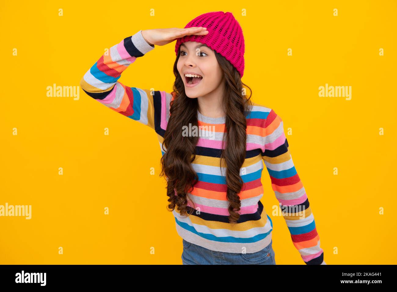 Modern teenage girl 12, 13, 14 year old wearing sweater and knitted hat on isolated yellow