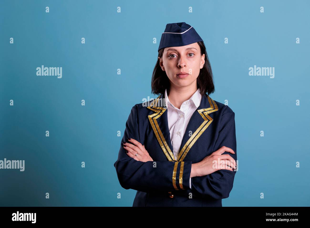 Young flight attendant wearing uniform portrait standing with crossed