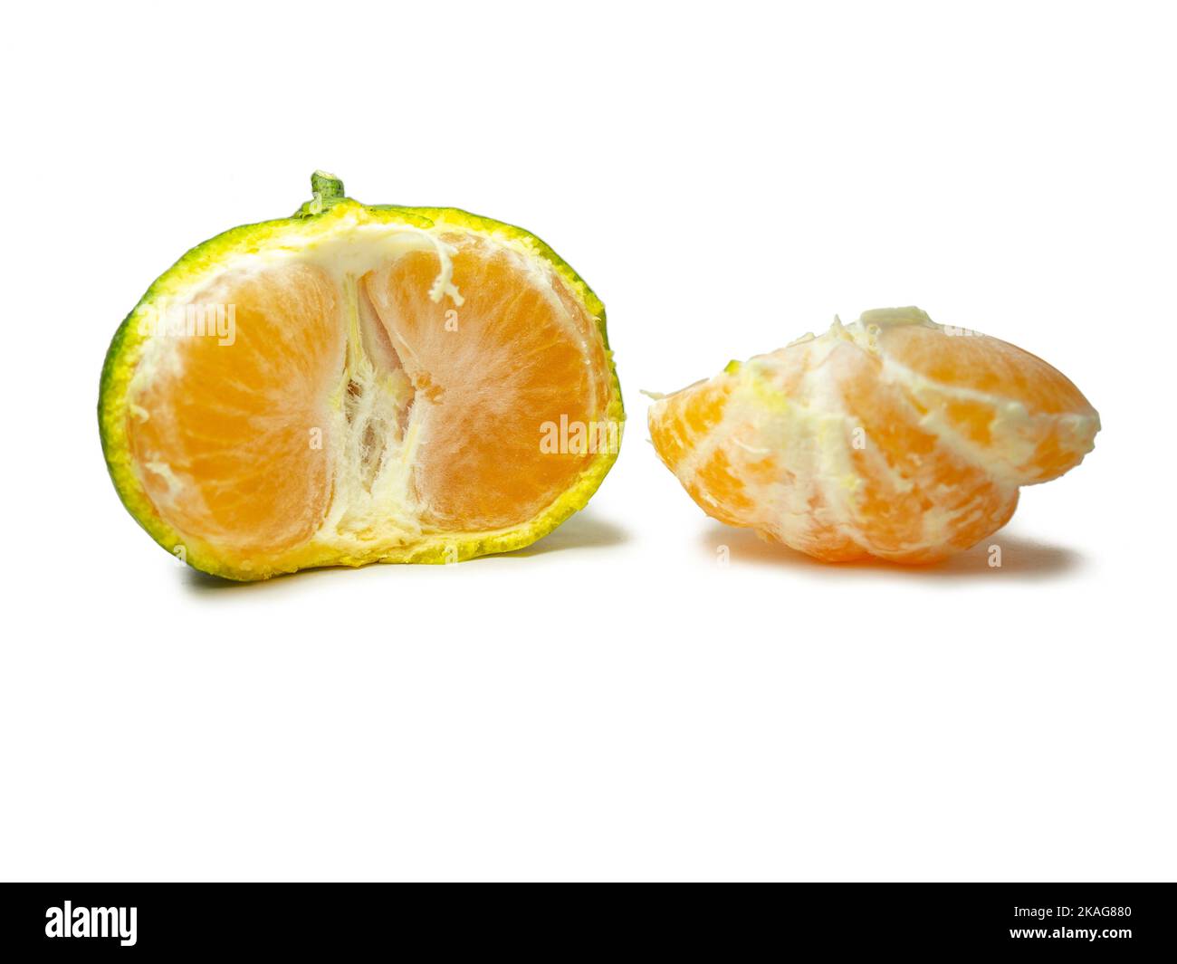Unripe tangerine. Peeling a tangerine. Green fruit on a white ...