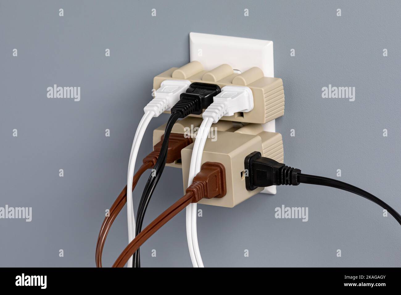 Electrical outlet overloaded with extension cords and adapters. Electricity safety, fire hazard and circuit overload concept Stock Photo