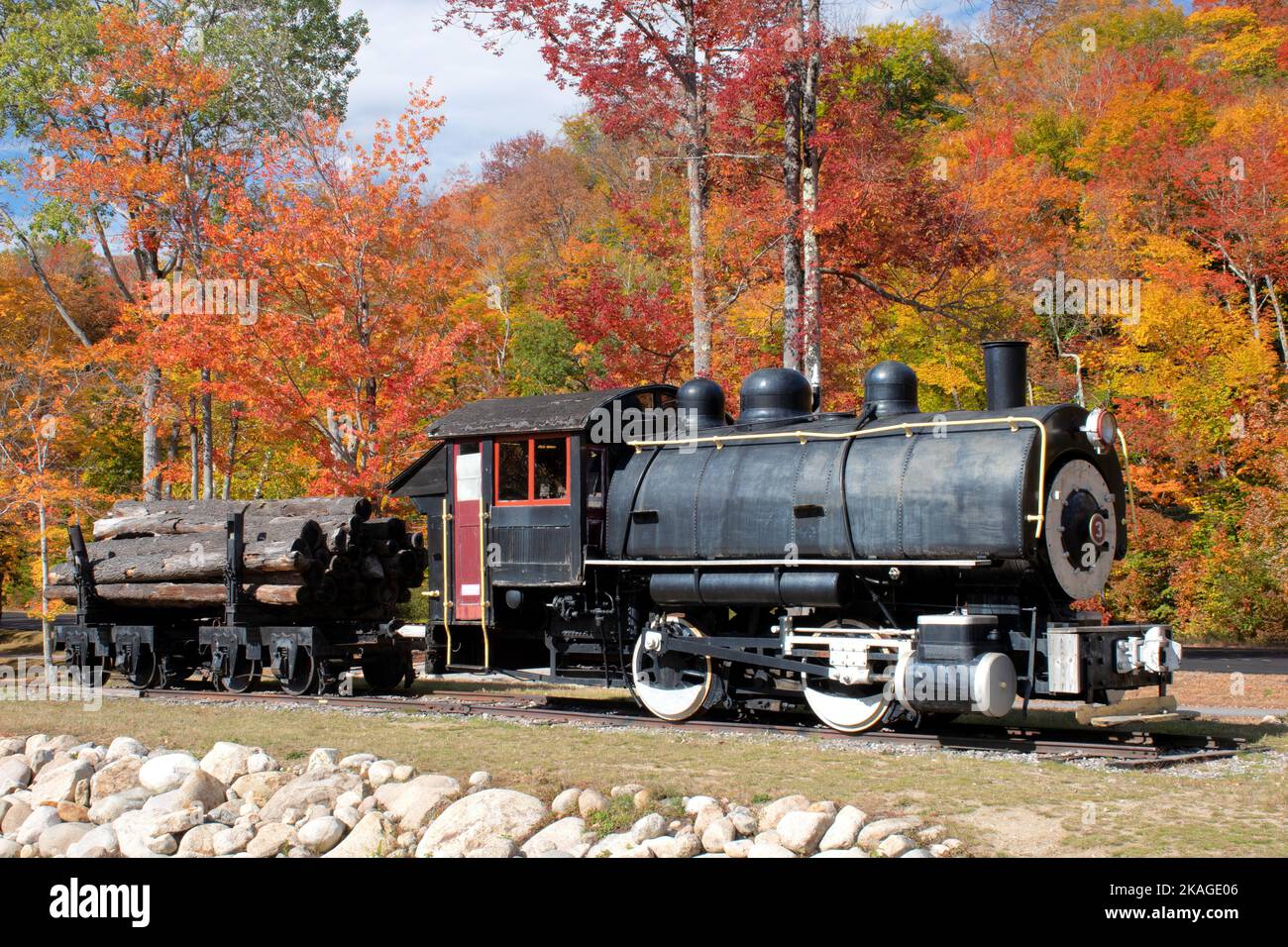 Colorful fall foliage and steam-powered Porter Locomotive coupled to freight car. Used for hauling logs harvested in White Mountains of New Hampshire. Stock Photo