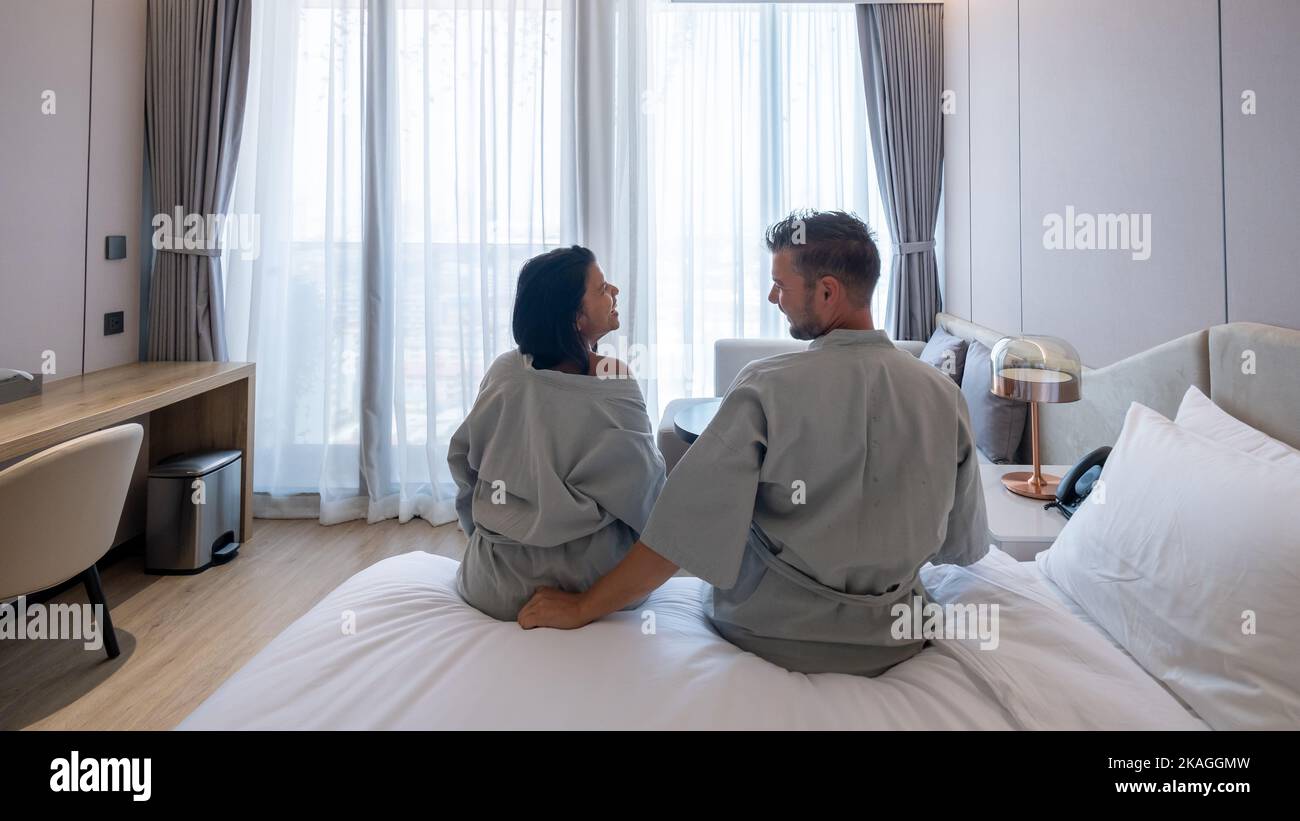 couple waking up in a hotel bedroom, Thai Asian women and Caucasian men waking up in a bed of a luxury hotel. Stock Photo