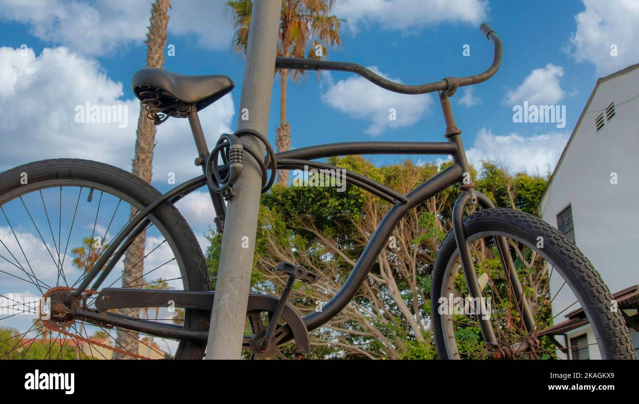 Panorama White puffy clouds Bicycle locked on a metal pole at La Jolla, California. Parked black bicycle on a lawn with cable lock against the view of Stock Photo
