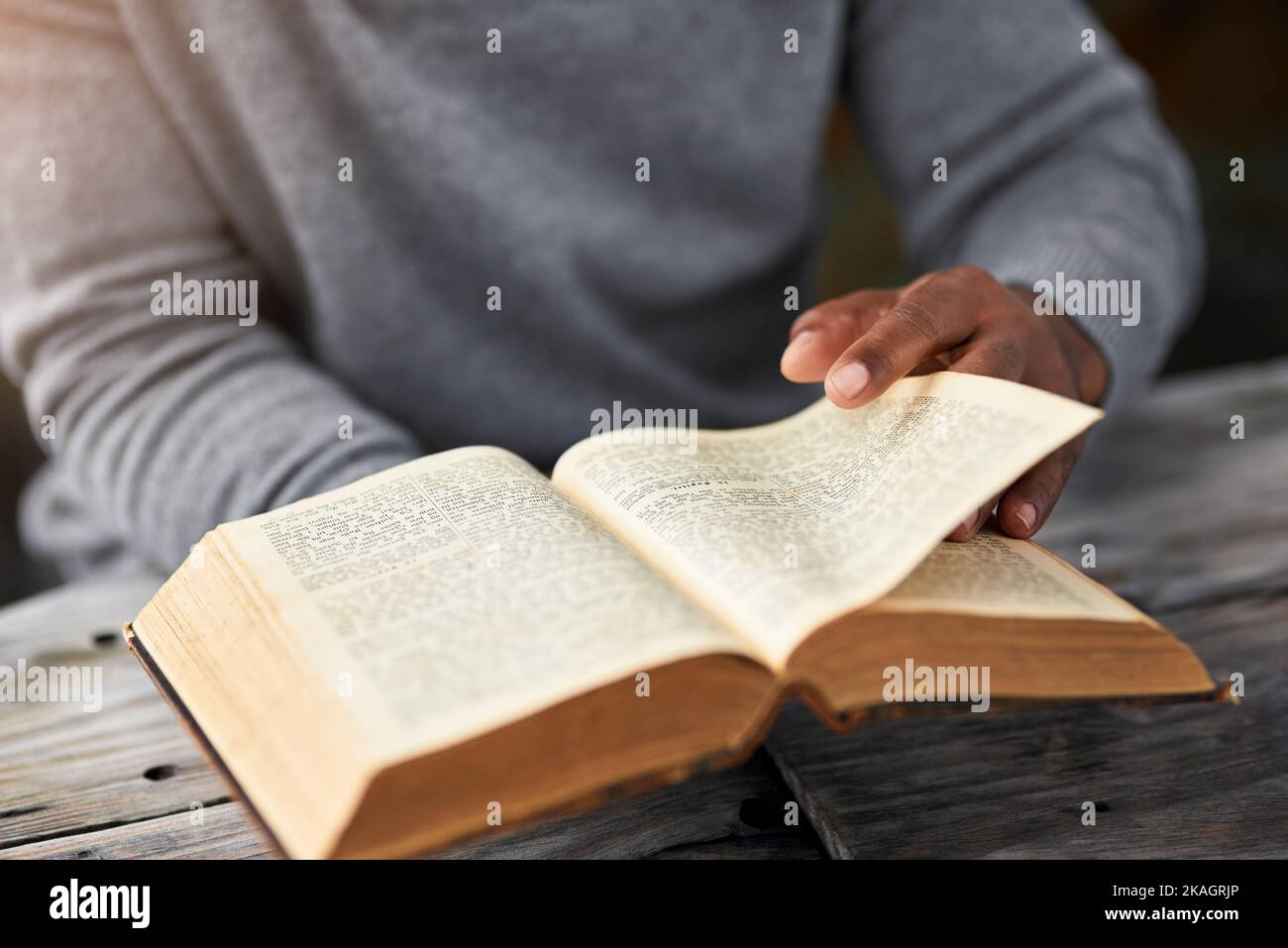 Its time to turn the page. High angle shot of an unrecognizable man reading his bible while sitting outside. Stock Photo