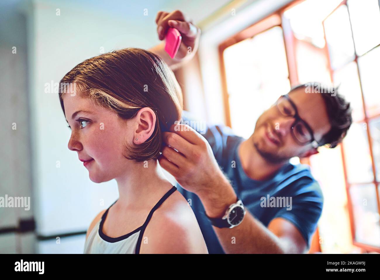 Hes truly involved in every part of her life. a father combing his little daughters hair at home. Stock Photo