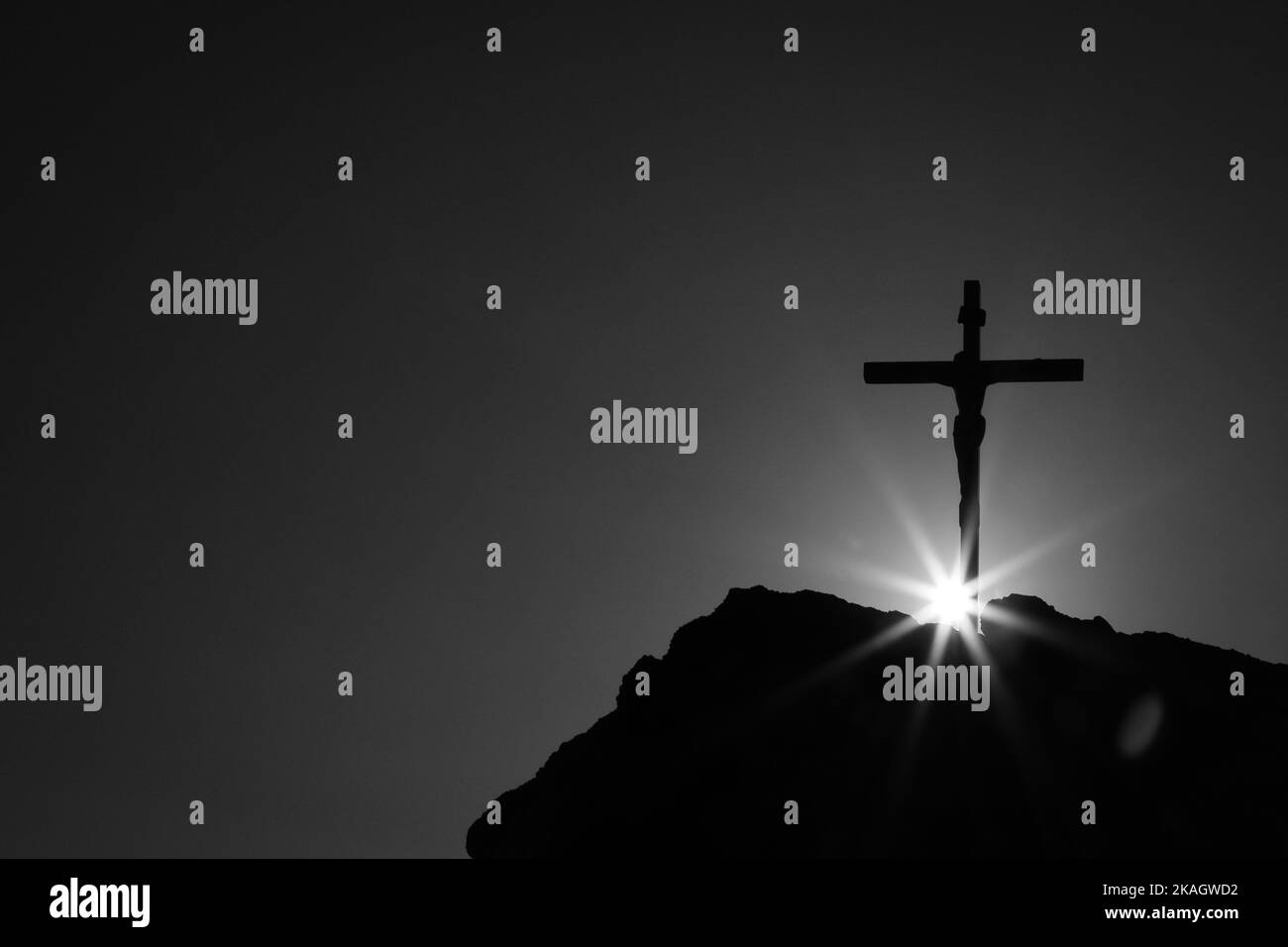A bright light shines between the dark background sky and Golgotha hill and the holy cross symbolizes the suffering, death and resurrection of Jesus C Stock Photo