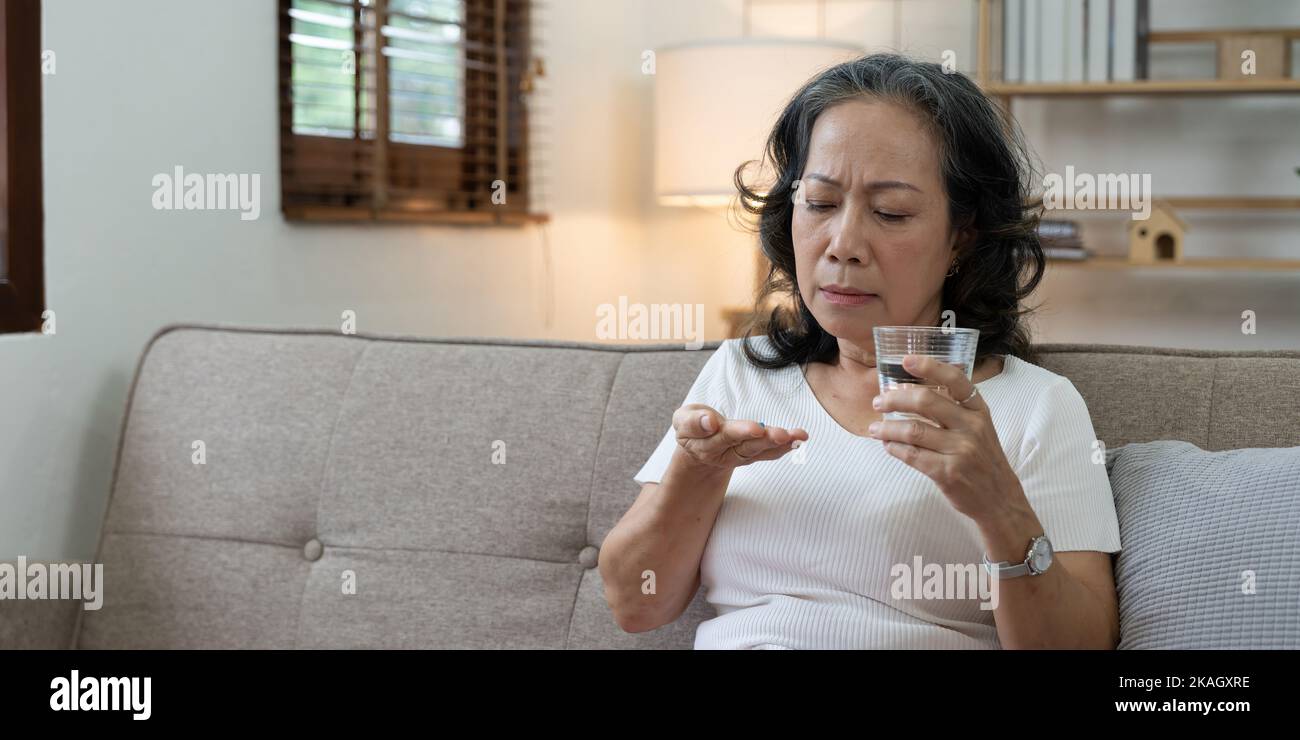 Elderly sick ill woman hold pills on hand pouring capsules from