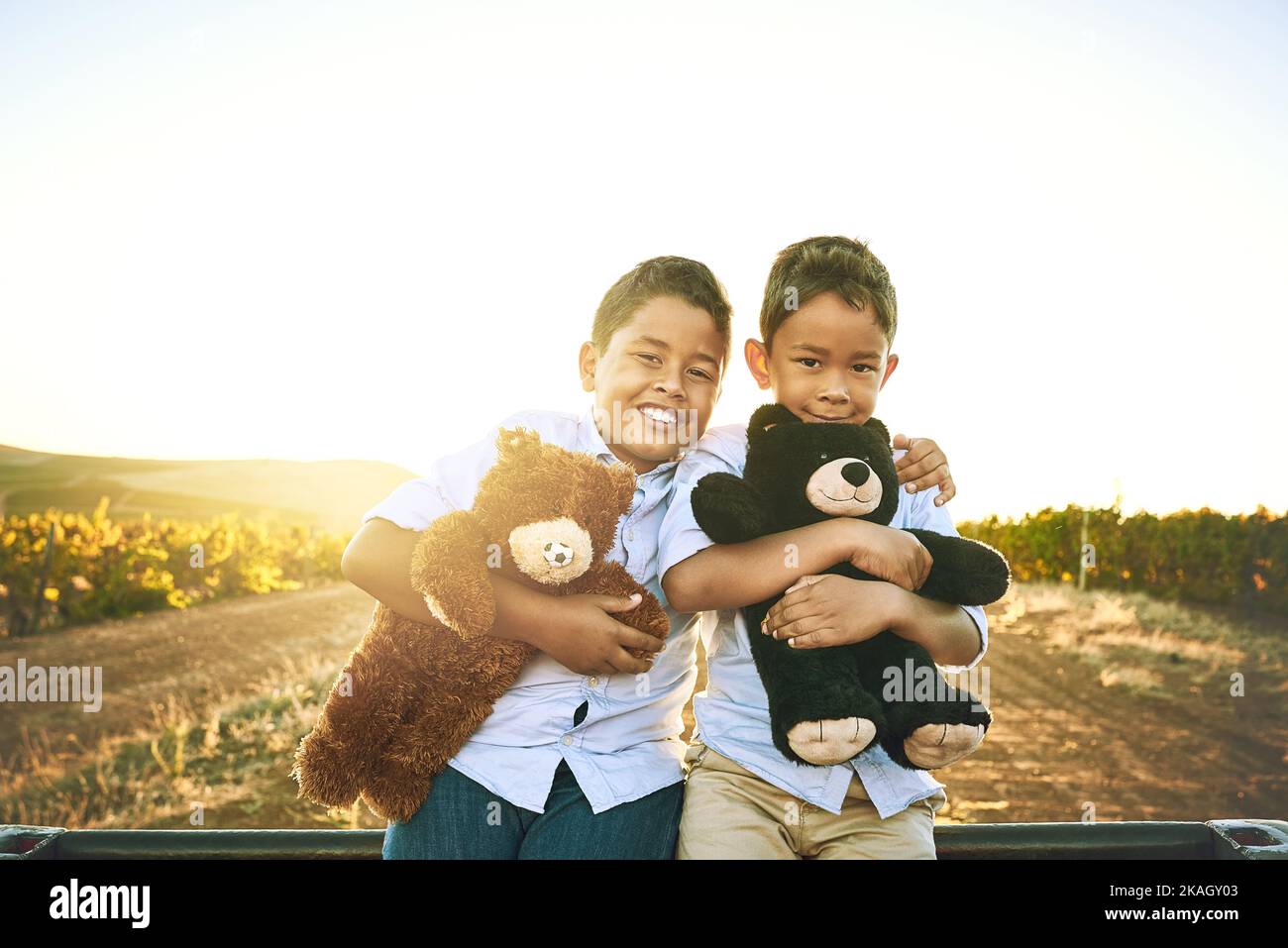 We always bring them along on our adventures. Portrait of two little brothers playing with teddy bears outdoors. Stock Photo