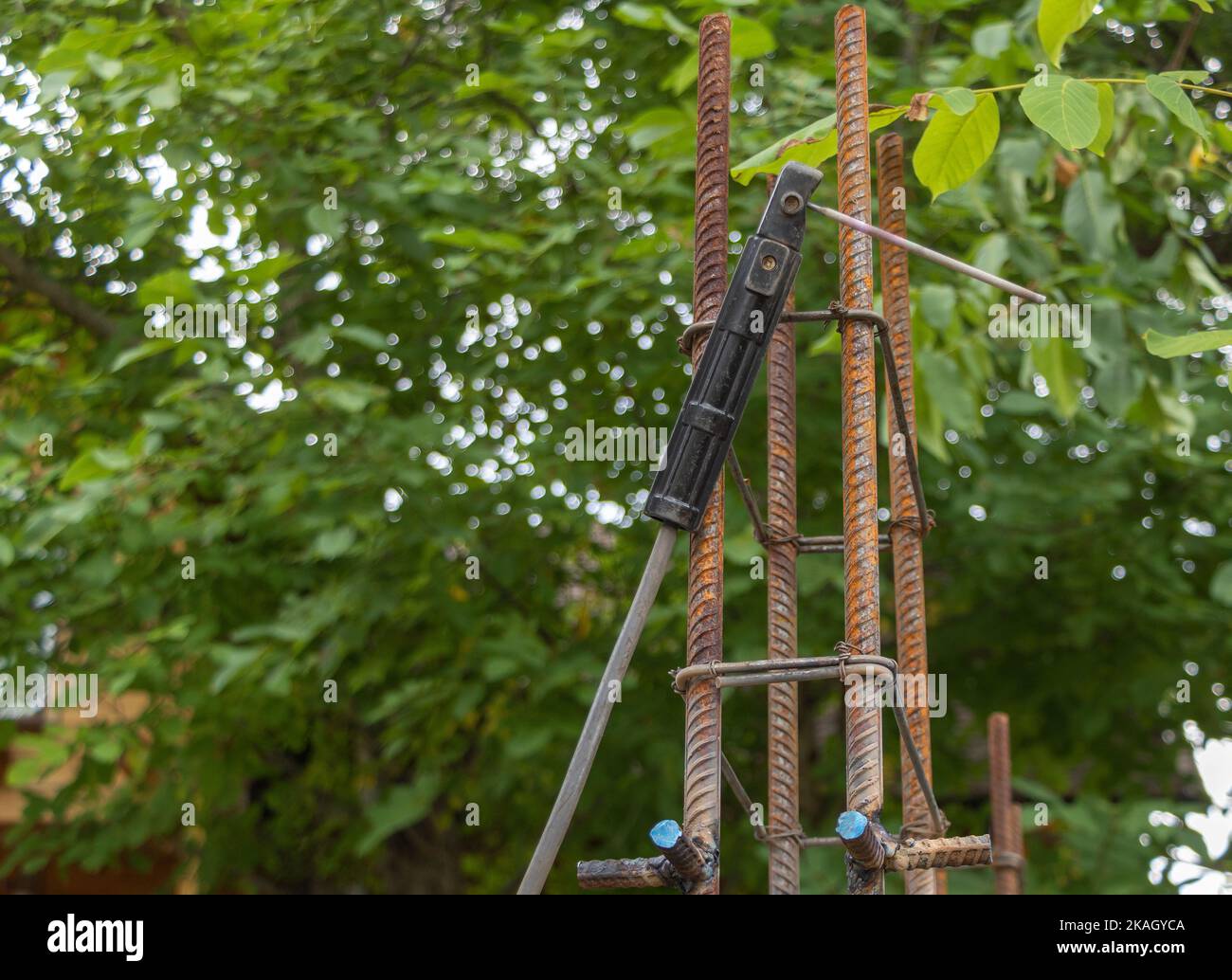 A welding torch hanging from the armature column - construction concept. Green nature background. Stock Photo