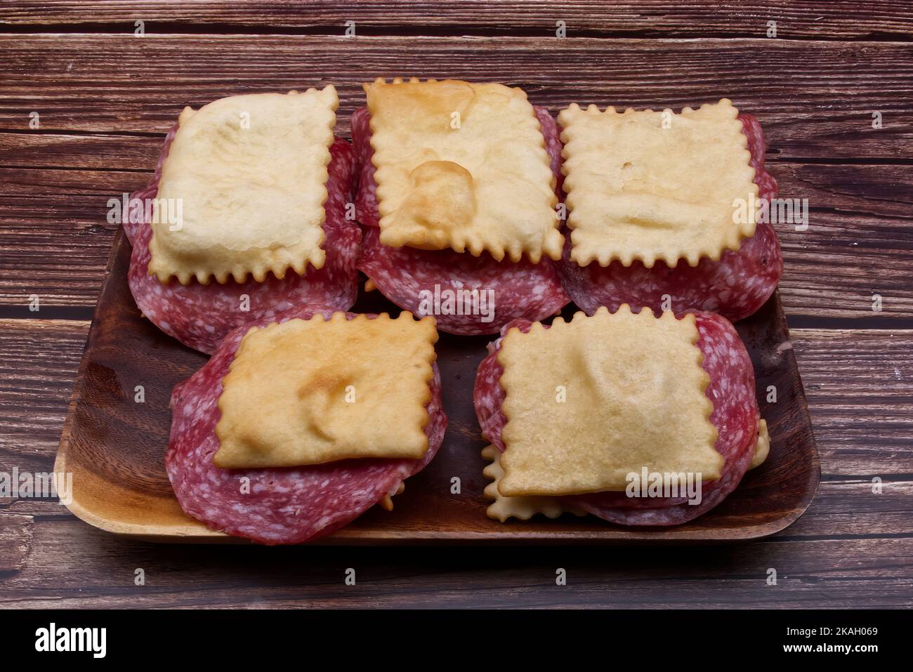 Gnocco Fritto with salami on rustic wooden table. Italian substitute