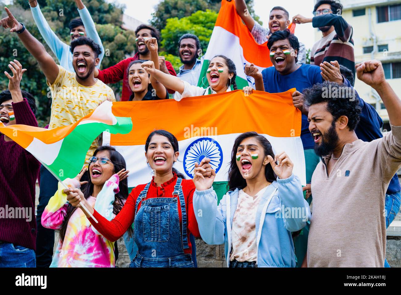 Group of audience at stadium shouting, screaming for win by holding indian flags while watching crcket sports match at stadium - concept of Stock Photo