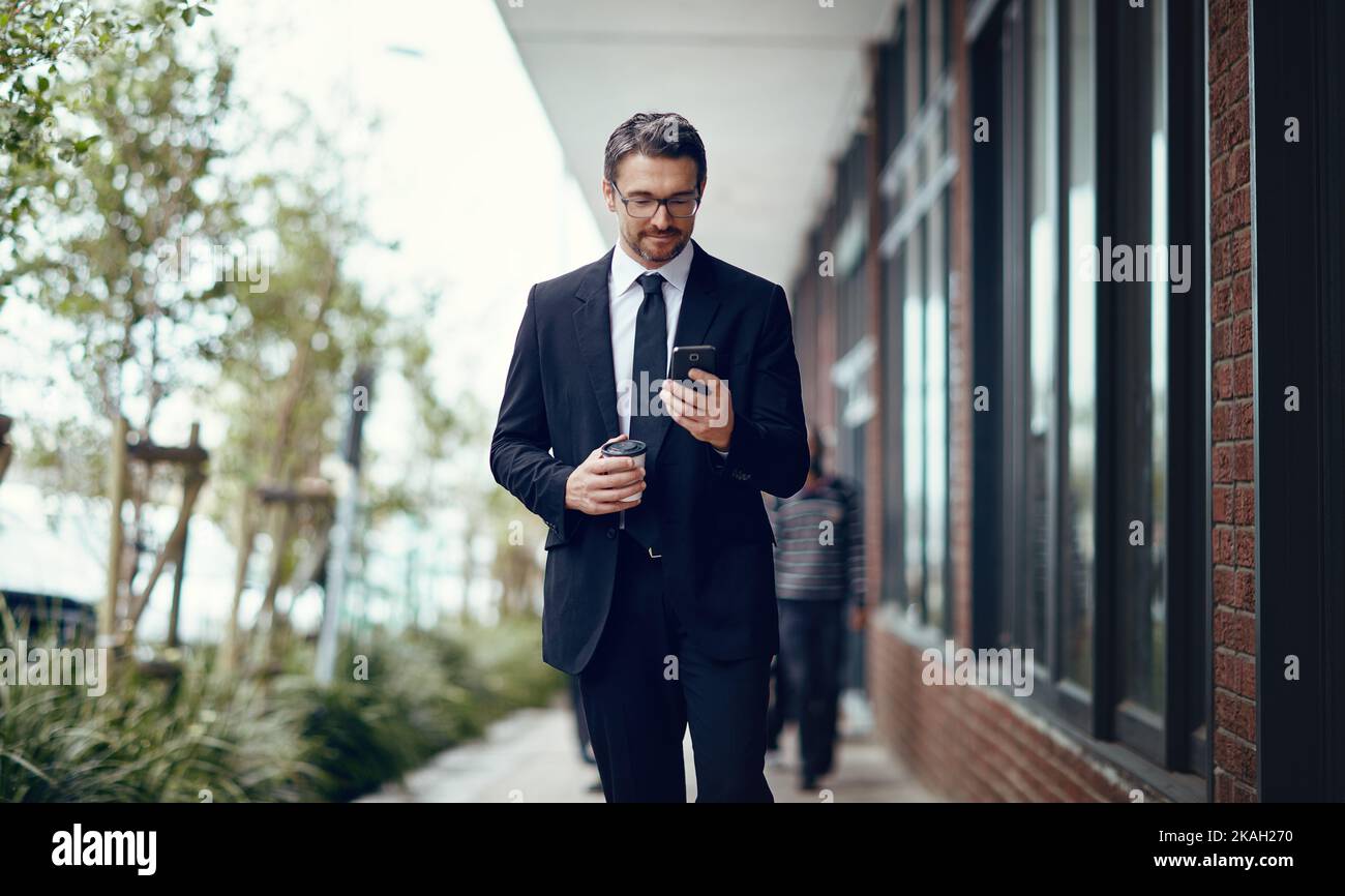 Just stepped away from my desk for a quick coffee. a mature businessman texting on a cellphone while out in the city. Stock Photo