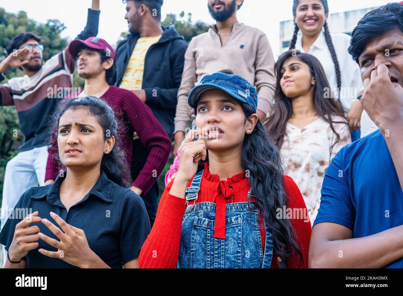 Serious tensed audience watching cricket sports match at stadium by biting nails - concept of tournament, championship and hopeful Stock Photo