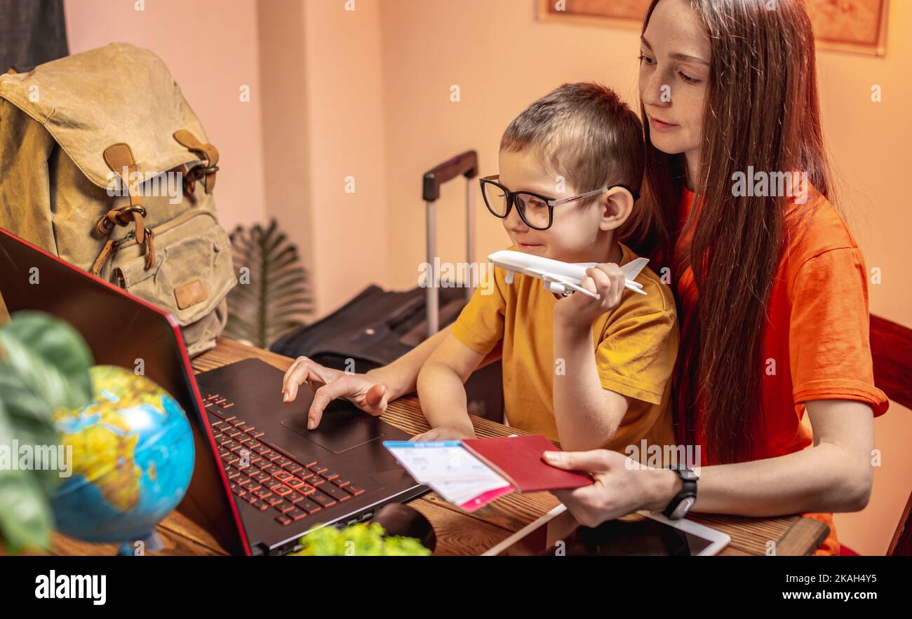 Mom and child buy airline tickets online at home with a laptop. Travel