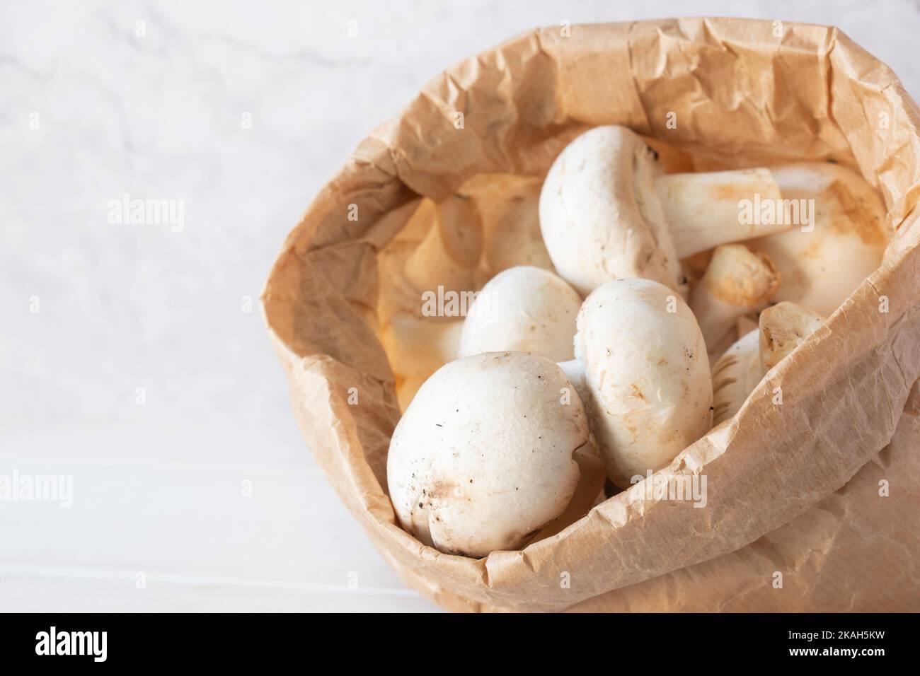 Closed cup mushrooms in a brown paper bag. Eco friendly recycling compostable packaging. Stock Photo
