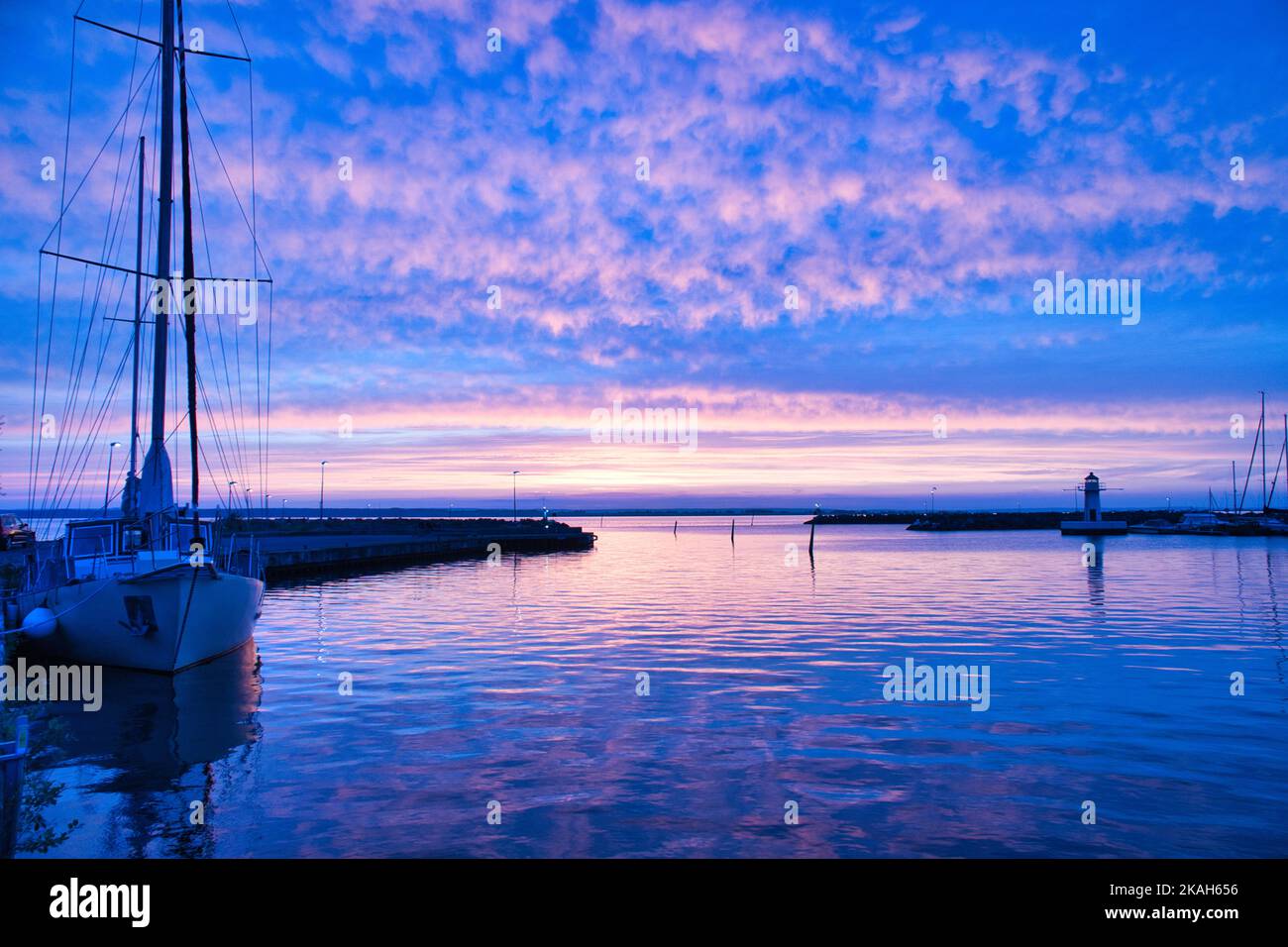 Sailing ship in the harbor of lake Vaettern at sunset. Lighthouse in ...