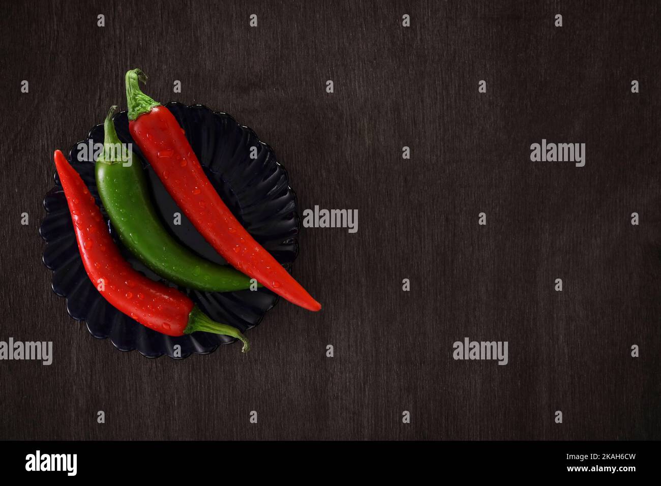 Stinging chili peppers on a black wooden background. Copy space for text. Stock Photo