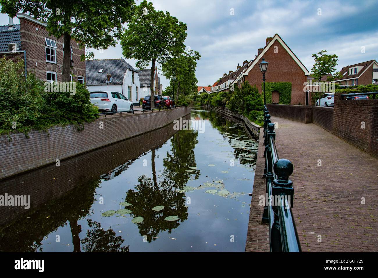 Road and brick houses by a canal in the Netherlands. Summer