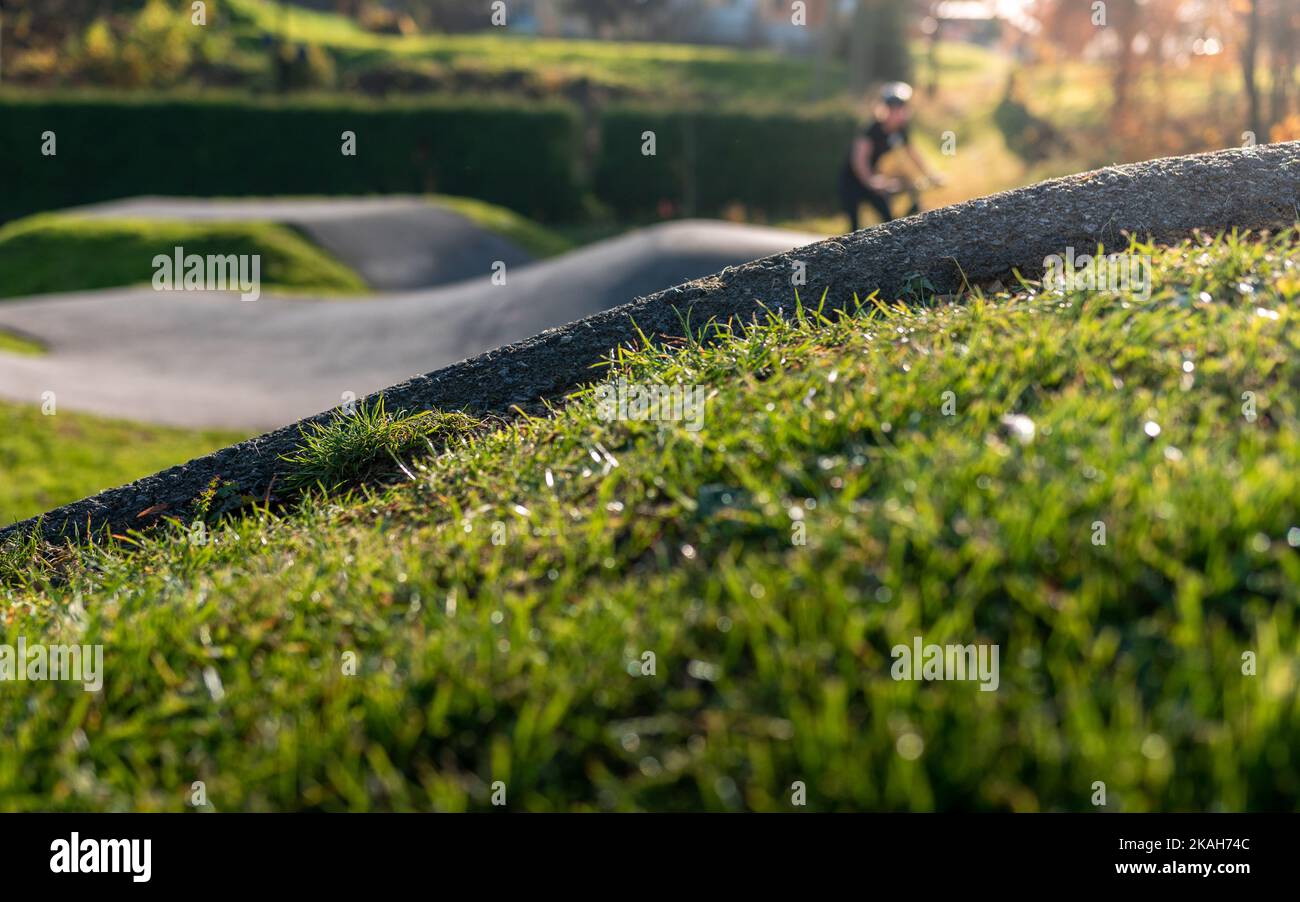 Bumpy Running Track Blurred biker riding on an asphalt pump track surrounded by nature on a ...