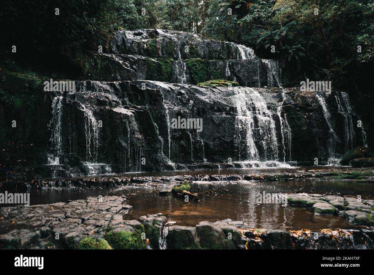 beautiful waterfalls falling down the big rocks among the greenery of ...