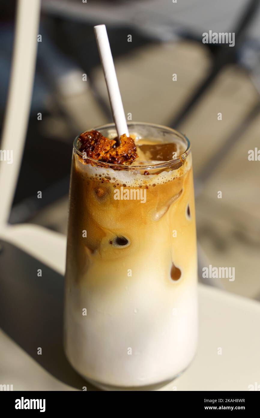 Dalgona coffee. Iced coffee drink with sugar and milk on a glass cup on a table in a cafe. Trendy cold drinks, Korean food concept. High quality photo Stock Photo