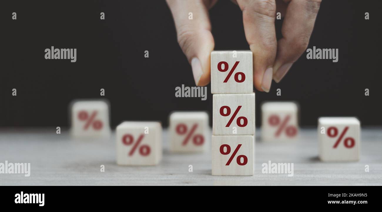 Interest rate financial and mortgage rates concept. Hand putting wood cube block increasing on top with icon percentage symbol upward direction Stock Photo
