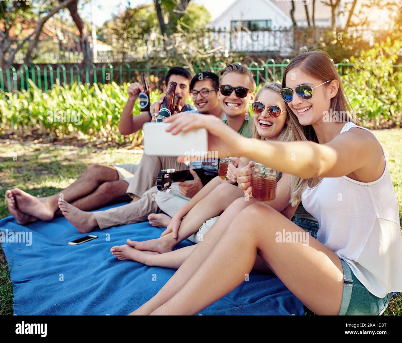 Lemme get one with all of us. a young group of friends taking selfies while enjoying a few drinks outside in the summer sun. Stock Photo