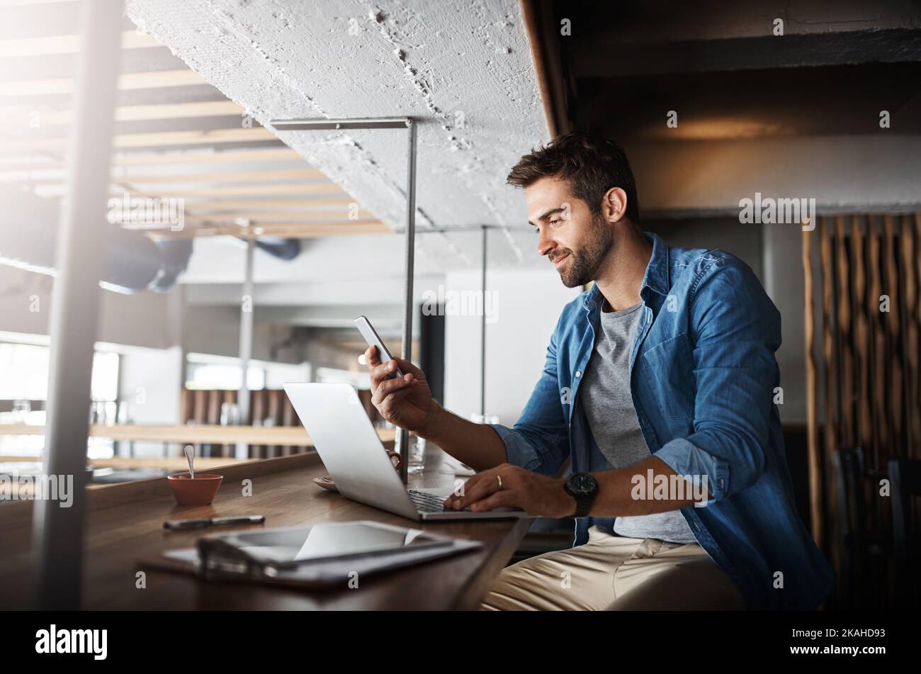 Everyday is an opportunity to expand his business. a handsome young man using a laptop and phone in a coffee shop. Stock Photo