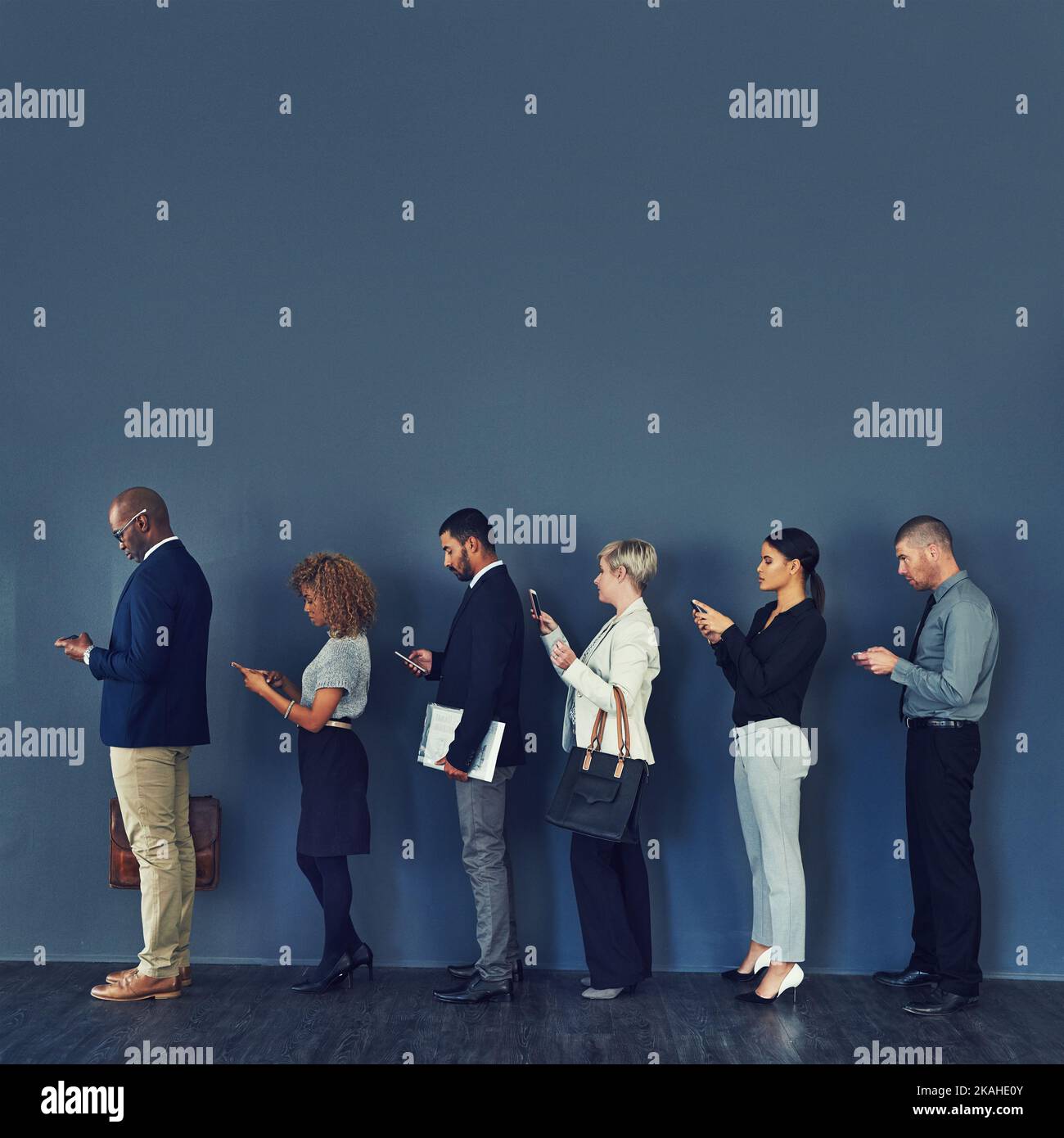 In line for opportunity. Studio shot of a group of businesspeople using wireless devices while waiting in line. Stock Photo