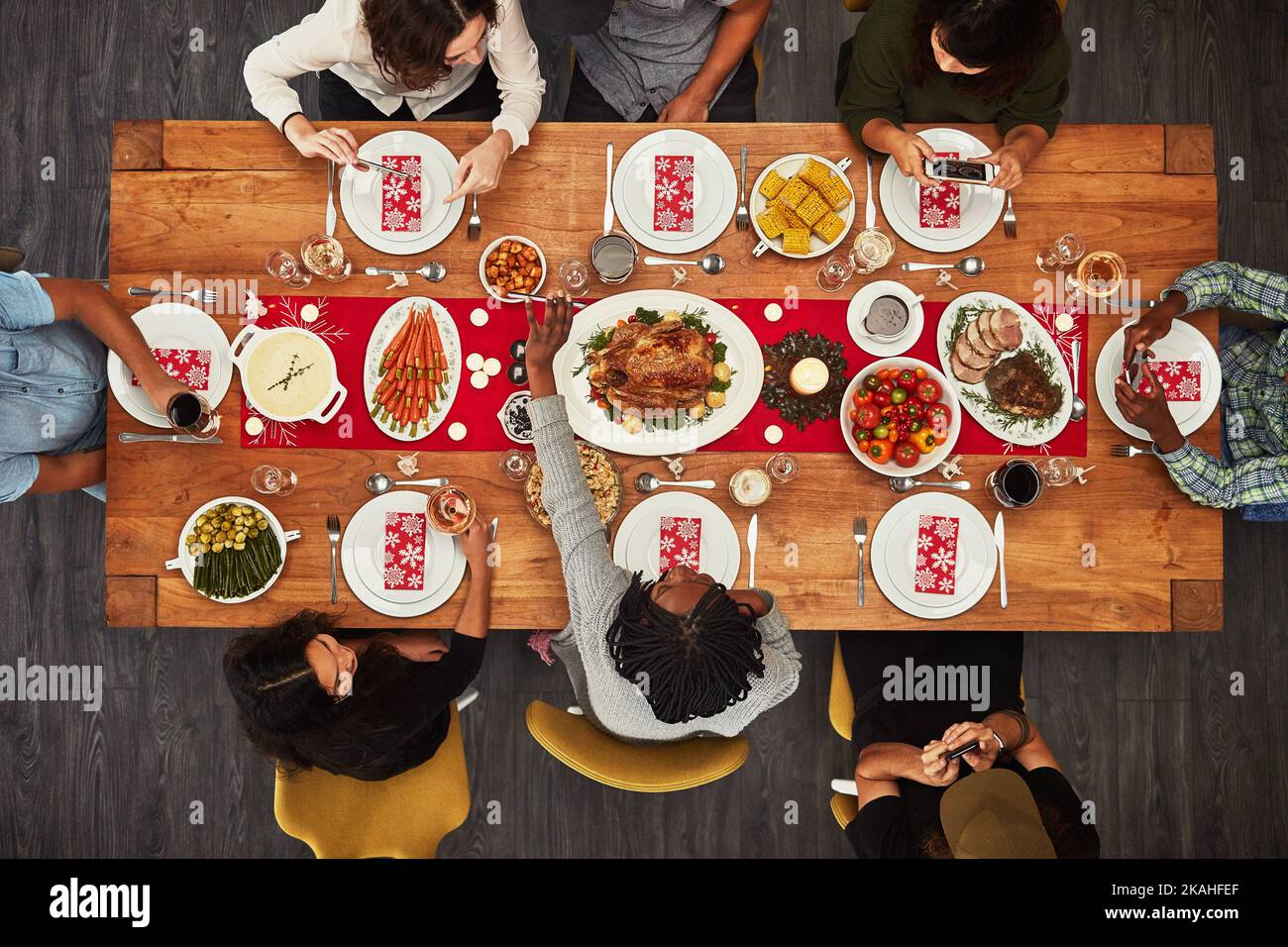 It wouldnt be a gathering without food. a group of people sitting together at a dining table ready to eat. Stock Photo