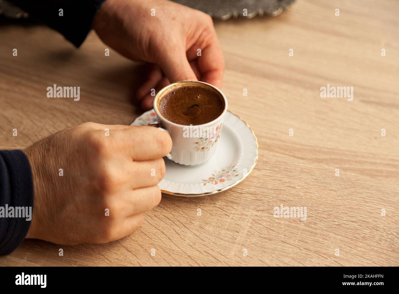 Traditional foamy turkish coffee in patterned white cup on oak coffee