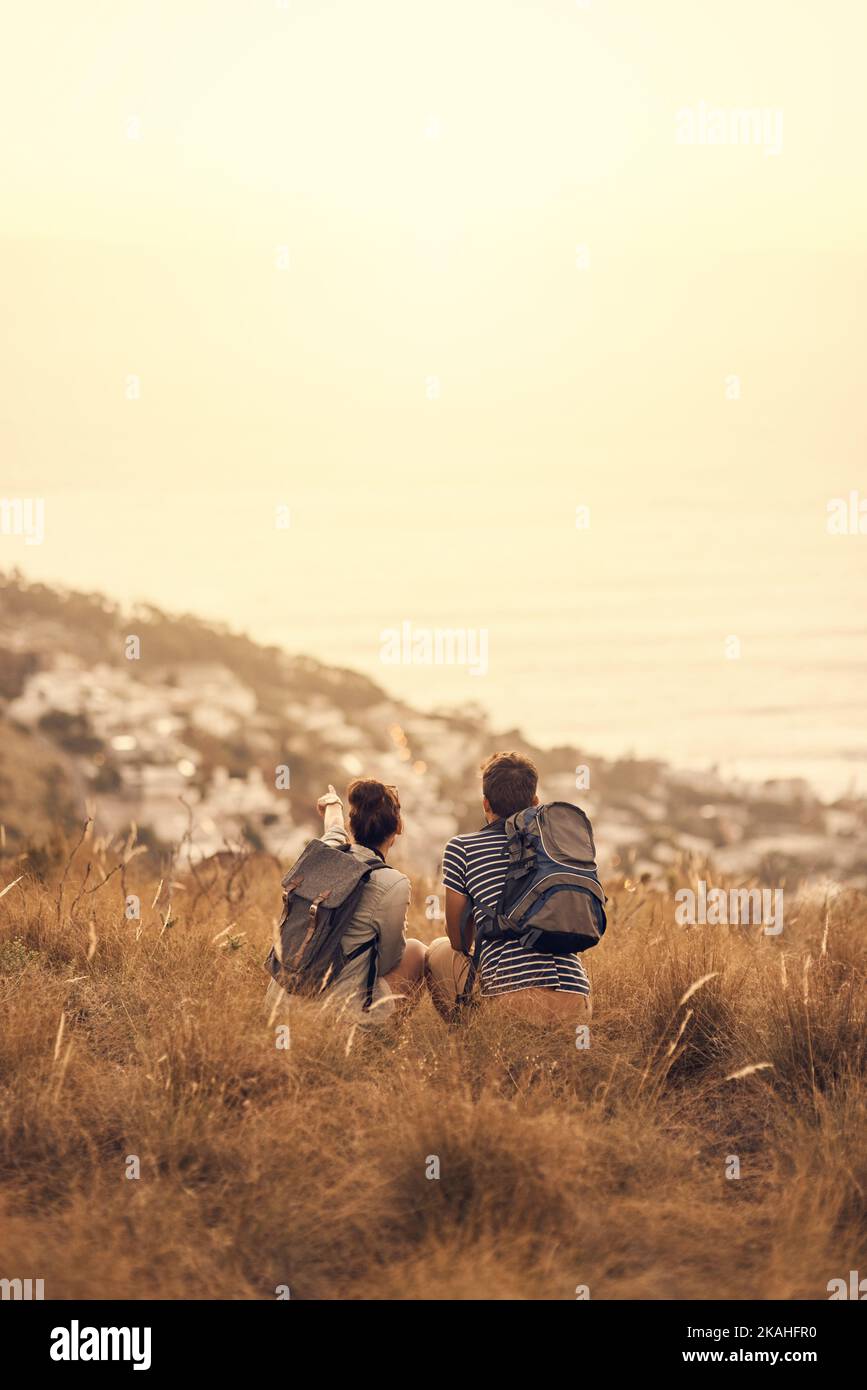 lets stay here forever. Rearview shot of a couple taking a break after hiking. Stock Photo