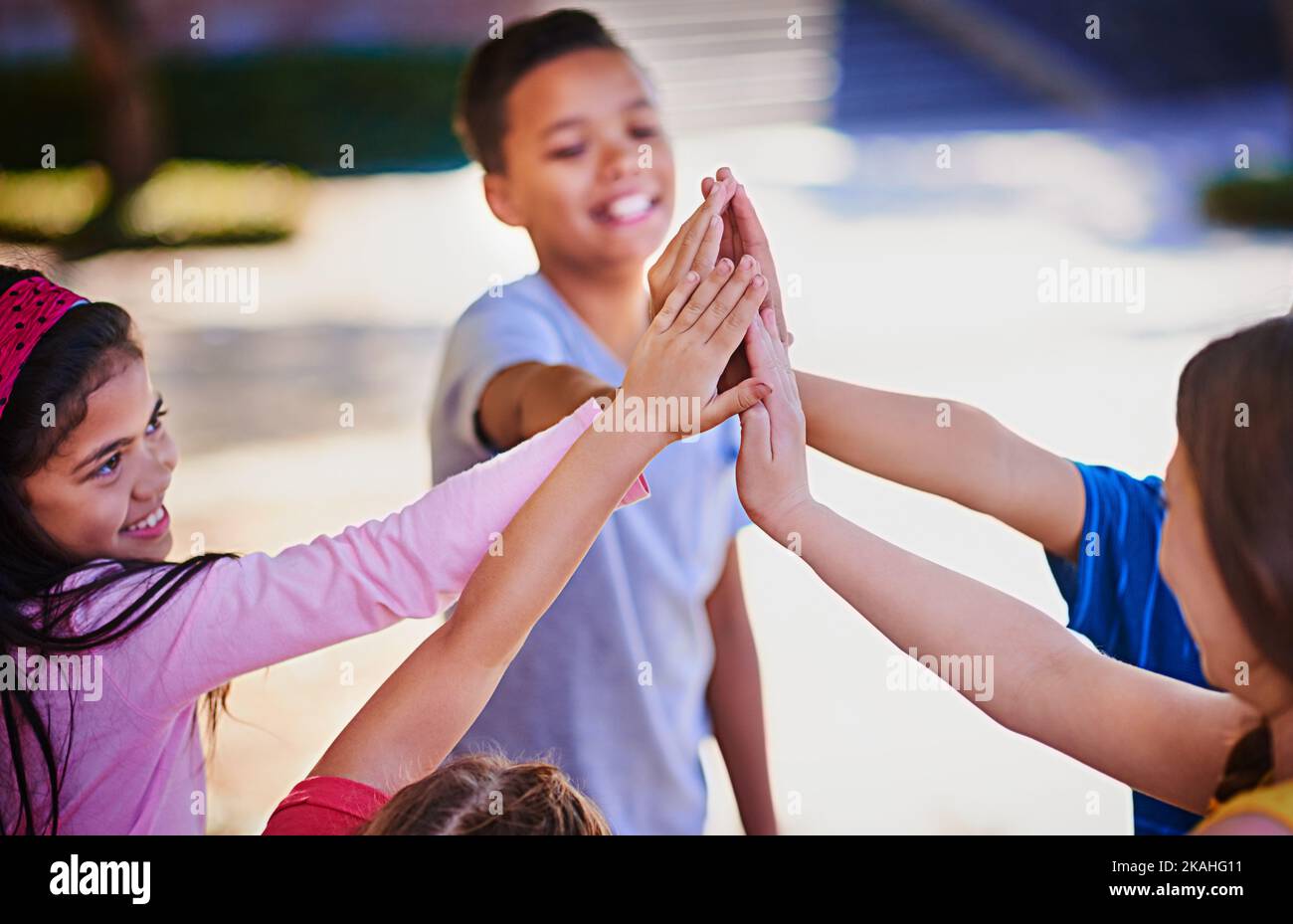 High five to having these awesome friends. a diverse group of children giving each other a high five outside. Stock Photo