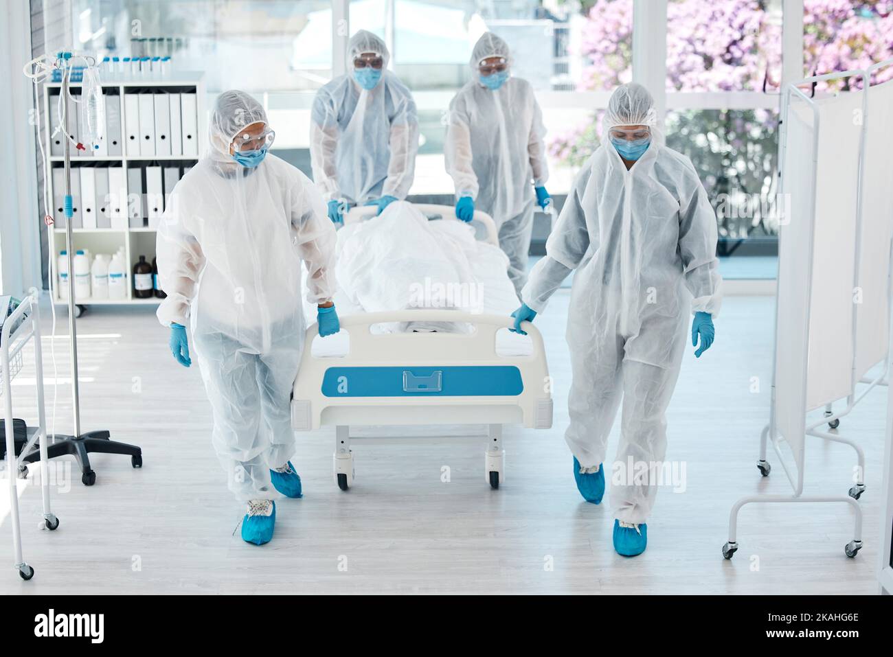 Covid, ppe and doctors with patient stretcher in hospital for