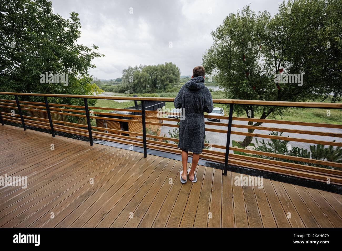Teenager boy in bath robe stand in wooden terrace of modern house Stock ...